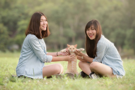 smiling beautiful young women sitting and playing with domestic cat outdoor happilyの写真素材