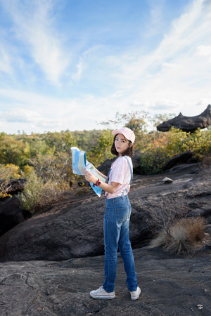 beautiful caucasian backpacker holding map in hand finding somewhere with nature backgroundの写真素材