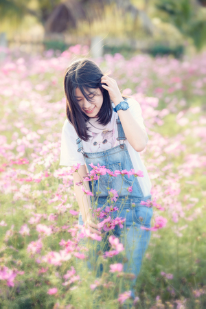 Beautiful Asian girl is smiling in pink cosmos flower fieldの写真素材