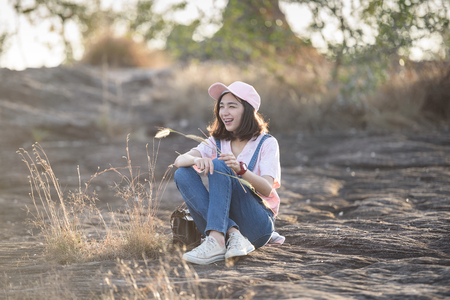beautiful caucasian girl holding grass flower in hand smiling with beautiful lightの写真素材