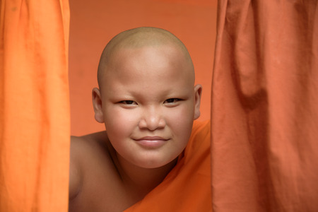 head shot of smiling Buddhist novice monk with yellow robe backgroundの写真素材