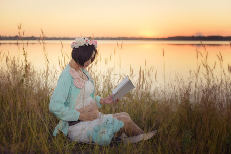 pregnant woman reading at sunsetの写真素材