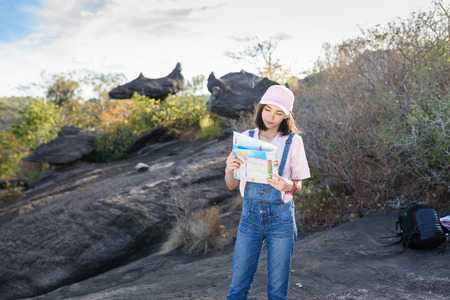 beautiful caucasian backpacker holding map in hand finding somewhere with nature backgroundの写真素材