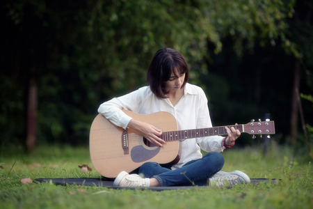 beautiful girl playing guitar in park, classic guitar, wooden guitar, chord guitar, solo guitar, acoustic guitarの写真素材