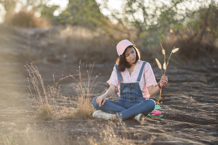 beautiful caucasian girl holding grass flower in hand smiling with beautiful lightの写真素材