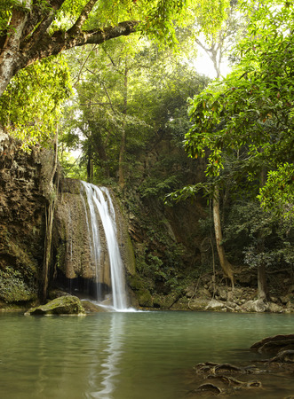 waterfall in forest with ray of lightの写真素材
