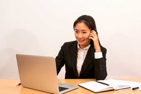 Asian woman call and check data from laptop on white backgroundの写真素材