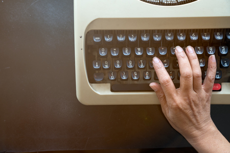 Close up of Senior secretarial typing the memo by old typewriter which placing on the rusty tableの写真素材
