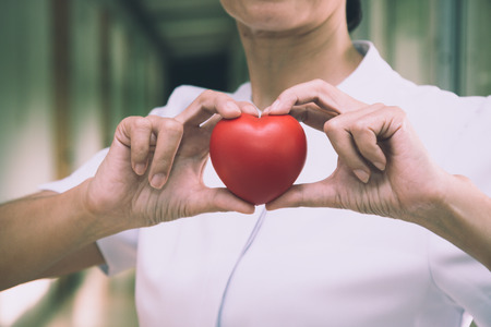 Senior female nurse holding red heart with love for Valentine's dayの写真素材