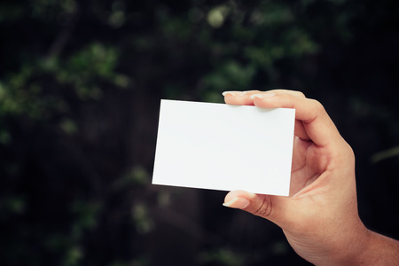 Woman's hand showing business card - closeup shot on nature backgroundの写真素材