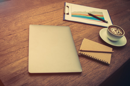 Flat lay of laptop with chart and  hot coffee placing on wood table which preparing before working with warm light flareの写真素材