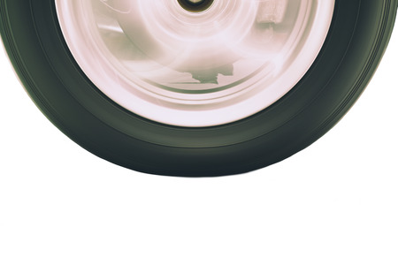 Close up of vehicle tire and rim rotation with blurry motion on white background with clipping path