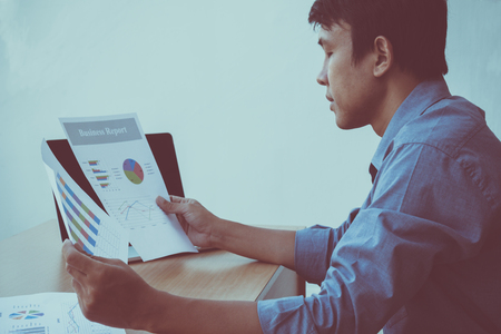 Middle aged thinking businessman working on laptop and checking the report while sitting at desk with clipping pathの写真素材