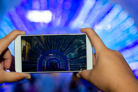 Man holding mobile phone and capturing the light illumination for Christmas and New Year dayの写真素材