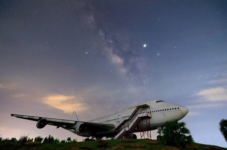Milky way rising up cross night sky over old airplane; long exposure shotting in night time