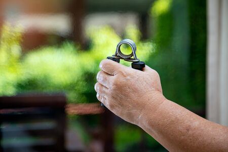 Close up of Senior Hand holding crush gripper. Aged woman squeezing and training hands for physical...