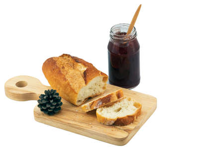 Fresh Homemade Sliced French Baguette Bread on wooden plate with jam bottle on white background