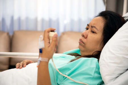 Woman holding and pushing hand emergency button in hospital patient room; Hand press to call Nurse...