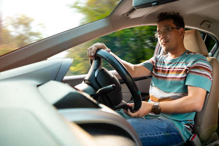 Asia 40s man in pain t-shirt driving to sight seeing by personal carの写真素材