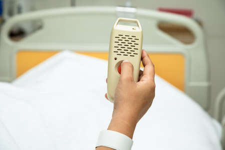 Woman holding and pushing hand emergency button in hospital patient room; Hand press to call Nurse for emergency caseの写真素材