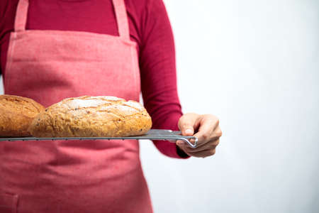 Asian female chef in red apron serve sourdough on metal net on white background