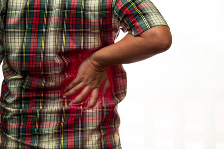 Close up 40s man got back pain and place hand at back with red color on whiteの写真素材