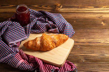 freshly baked sweet croissants on old wooden plate with jam and scottish cloth. Breakfast or brunch concept with copy spaceの写真素材