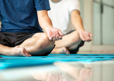 Close up mudra hand of two Asian young men sitting and practices yoga breathing meditation pose on...