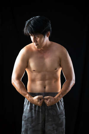 Young Asian man shirtless native pant posing strong body muscle on black backgroundの写真素材