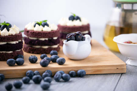 Close up blueberry in cup together row three cocoa cake on wooden board