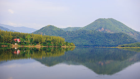 Beautiful red house in pines forest near mountain and lake. Mountains landscape and vintage wooden homeの写真素材