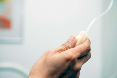 Close up hand holding and adjusting sliding infusion saline drop with copy spaceの写真素材