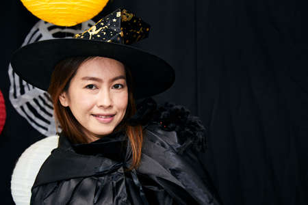 Asian young witch Halloween woman portrait and black spider on shoulder close up with copy space. Sorcerer makeup with Fashion art design as attractive model in Halloween costume on black backgroundの写真素材