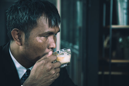 Asian elder businessman in suit and necktie drinking coffee and looking thinking concentrate with copy spaceの写真素材