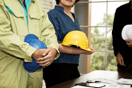 Three of Engineer secretary and chief Standing holding safety helmet in constrcution site meeting room, respect to project boss by close upの写真素材