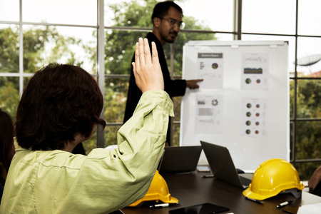 Female leader technician raise hand up to ask question to Chief site engineer during summary report presentation in meeting roomの写真素材