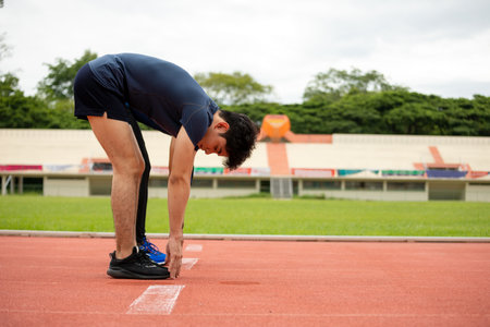 Two young Fit and confident Asian teenagers in starting position warm up stretching before running....