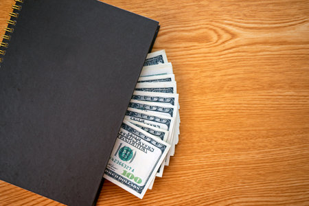 Financial Saving concept: Still Life of hundred Dollar Bank Notes in personal notebook on working...