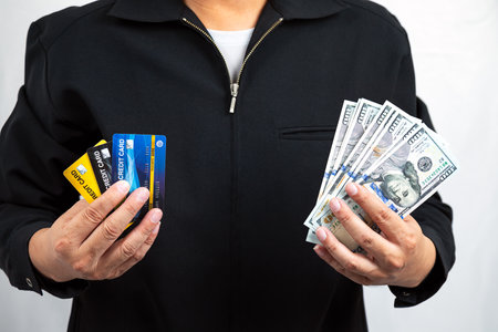 Man in Black Jacket Holding Credit Card and hundred Dollar Banknote in a Business Concept