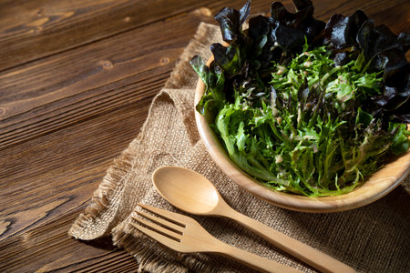 Healthy Green Vegetable Salad in wooden bowl on brown broad with Warm-Toned lighting; Farm-to-Table Diningの写真素材