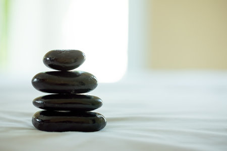 A stack of smooth black stones balanced perfectly, creating a sense of tranquility and focus in spa environmentの写真素材