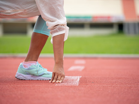 Close-up of runner in starting position on running track, ready to sprint, preparation for raceの写真素材