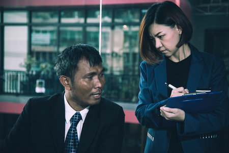 Asian businessman and secretary engaged in serious business discussion, conveying teamwork and strategic planning, close up shotの写真素材