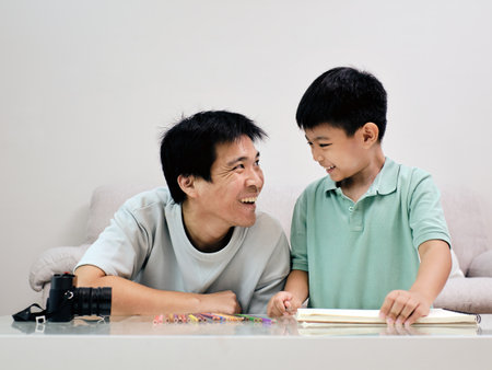 Joyful father and son sharing special moment together at home, engaging in fun and creative activity with smilesの写真素材