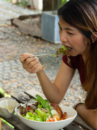 Girl eating salad in park.Healthy food and diet concept.の写真素材