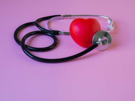 Red heart with stethoscope on pink background, heart health, heart disease, health insurance concept, world health day, doctor days.の写真素材