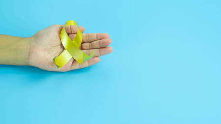 Hands hold gold ribbon, Sarcoma Awareness, Bone cancer, childhood cancer awareness, World Suicide...