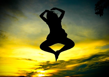 A happy woman jumping at sunset の写真素材