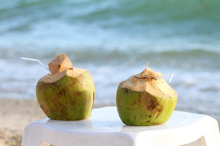 Coconuts with drinking straw on the chair at the sea の写真素材