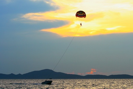 Man flying on parachute at sunset skyの写真素材